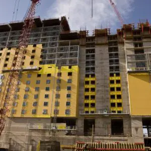 High-rise Hotel Under Construction With Yellow Sheathing Panels And Scaffolding In Place.
