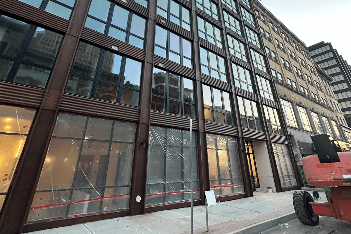 Contemporary building facade with large windows framed by dark metal and angled structural elements.