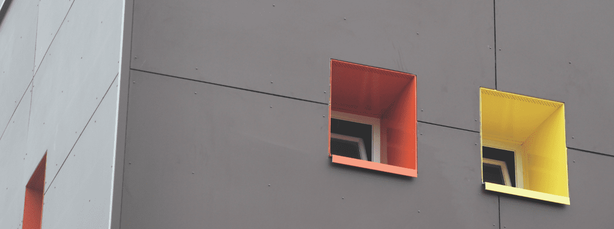 Fiber cement rainscreen facade with bold red and yellow window surrounds demonstrating architectural design flexibility