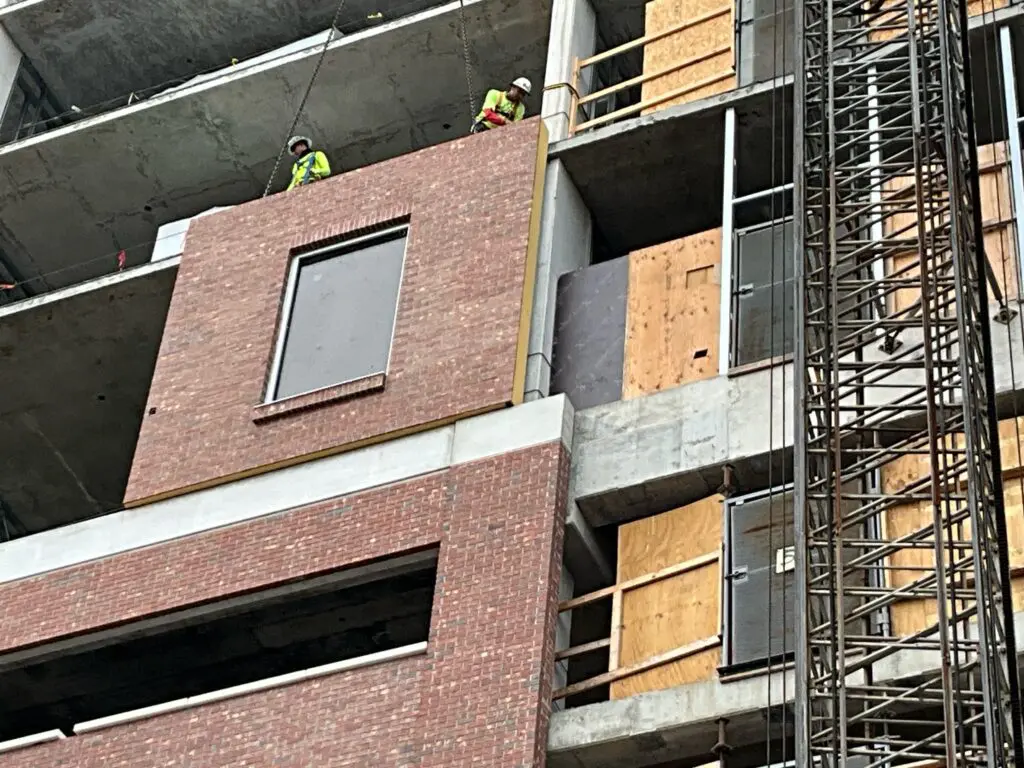 Prefabricated facade panels being installed on a multi-story building at the University of Tampa, illustrating efficient construction and system coordination