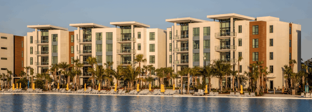 Waterfront multifamily building with light-colored facade designed for long-term exterior durability