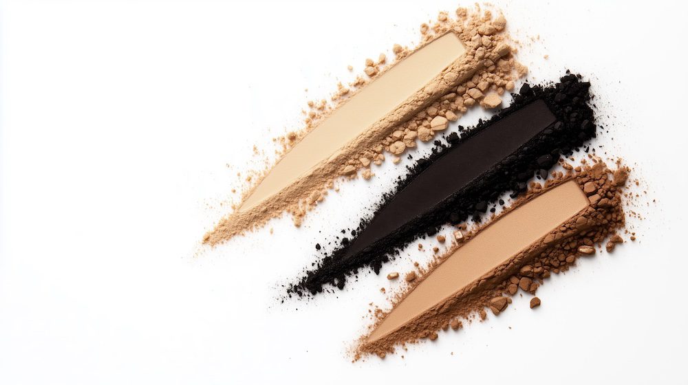 Earth tone pigment stripes with scattered powder on white background.