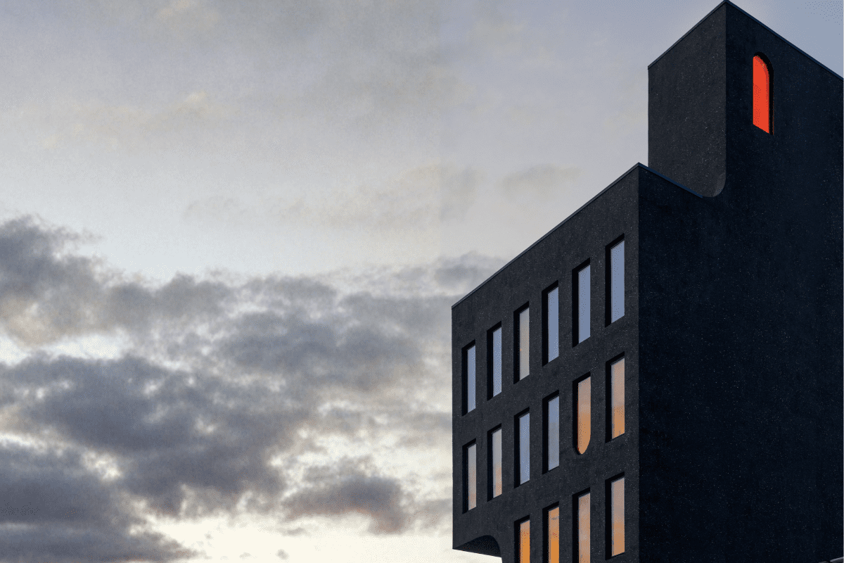 Modern mid-rise building with large grid-pattern windows and dark metal framing during construction.