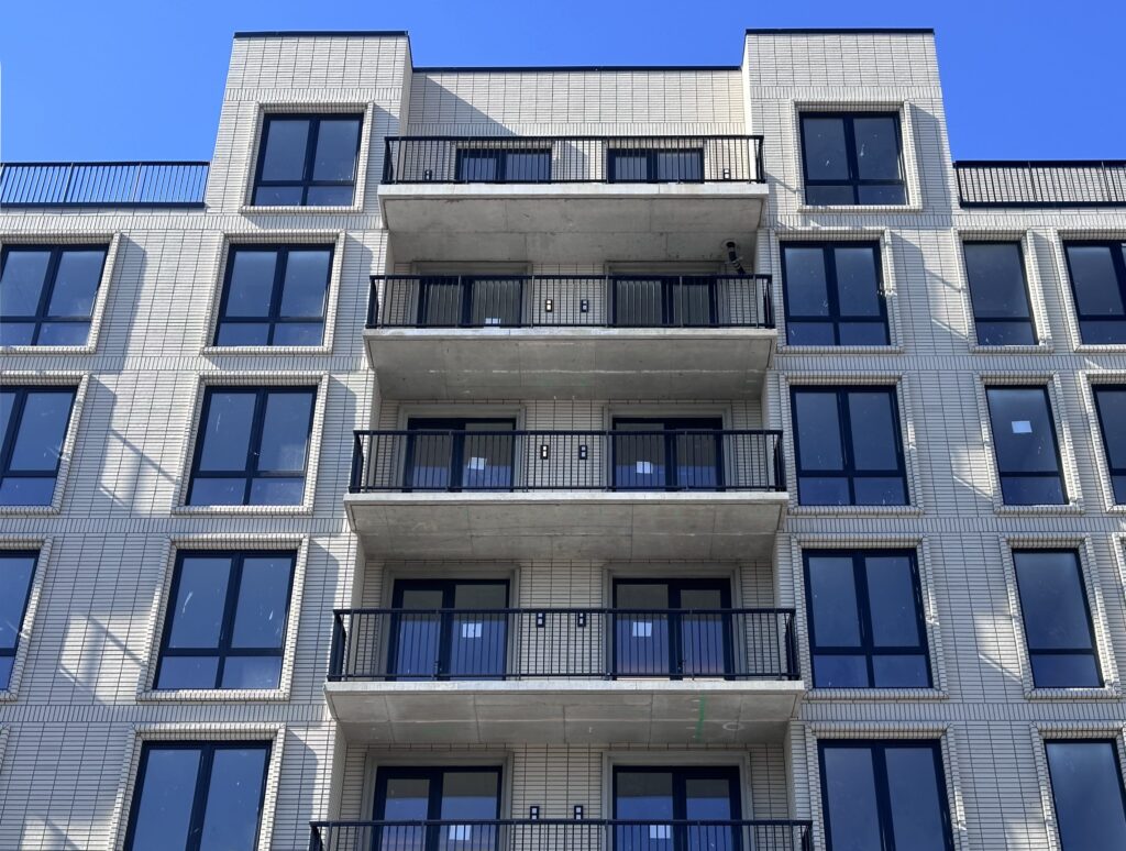 Multi-story residential building with repeating balconies and a consistent fa&ccedil;ade system designed for durability and long-term performance