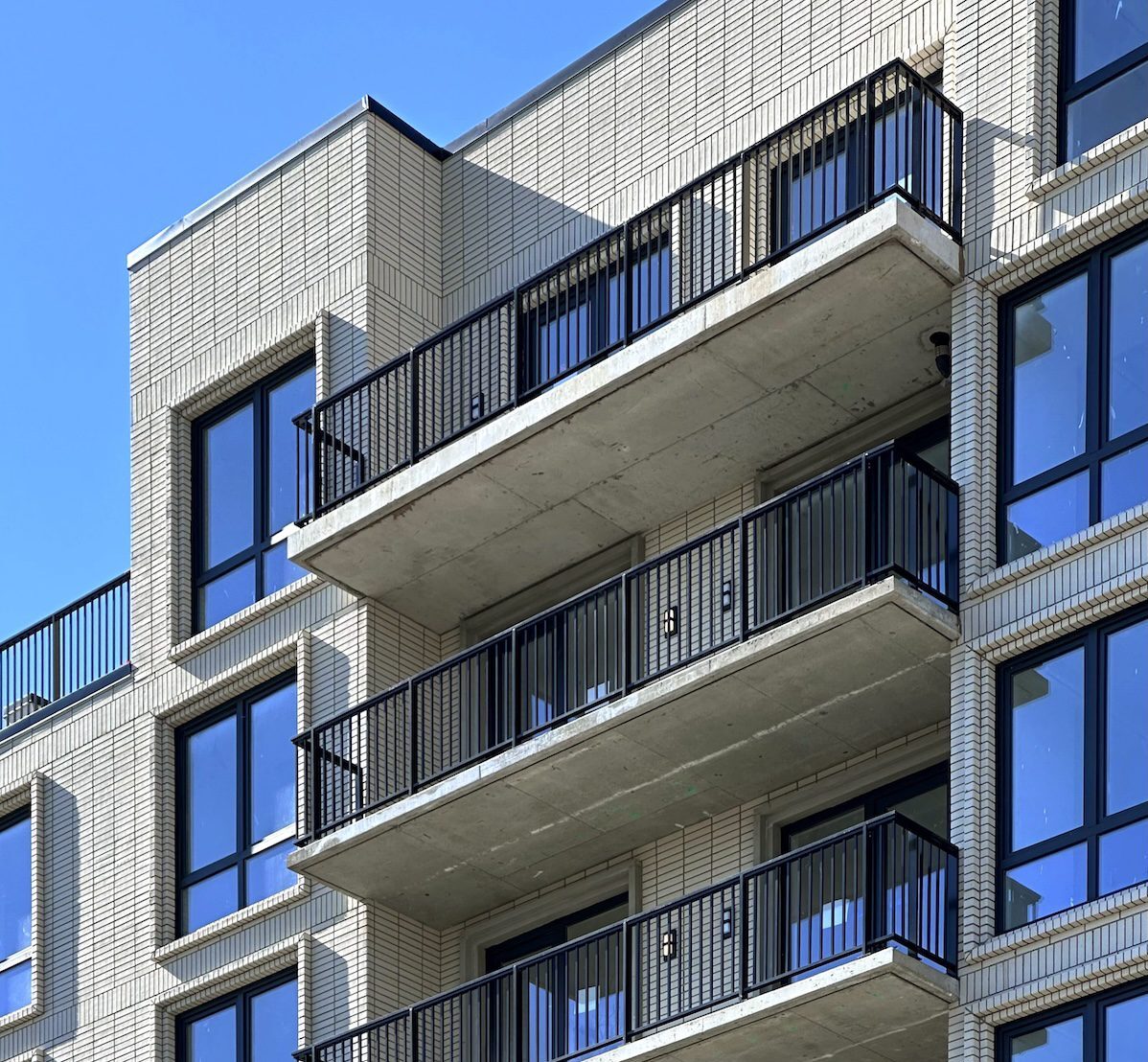 Contemporary residential building featuring light brick facade and integrated balconies demonstrating architectural design flexibility with lightweight cladding