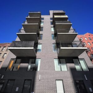 Modern Multifamily Building With Dark Brick Facade And Projecting Concrete Balconies Designed For Durability In High-traffic Urban Environments