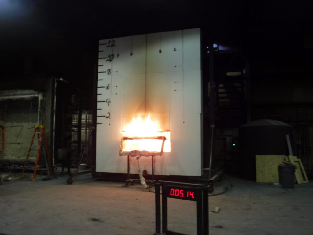 NFPA 285 fire test showing flame spread from a window opening on a two story wall assembly with a height measurement scale